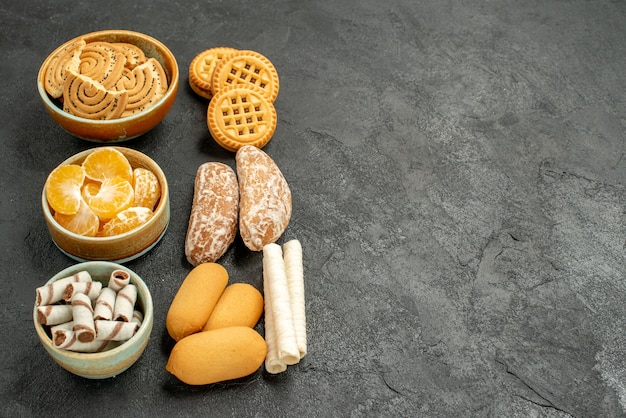 Biscoitos doces de frente com biscoitos e frutas no biscoito doce de mesa cinza