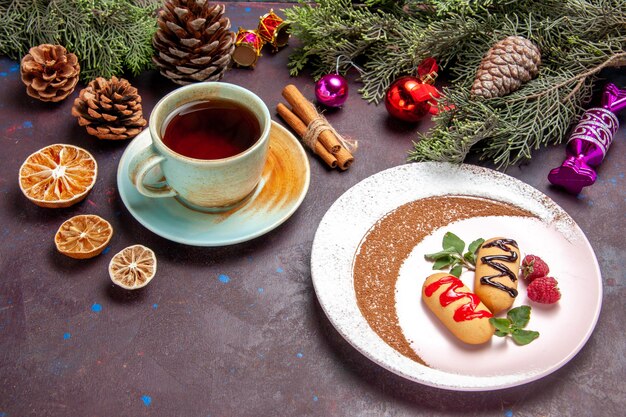 Biscoitos doces deliciosos com uma xícara de chá no espaço escuro de vista frontal