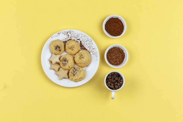 Biscoitos e grãos de café em um fundo amarelo