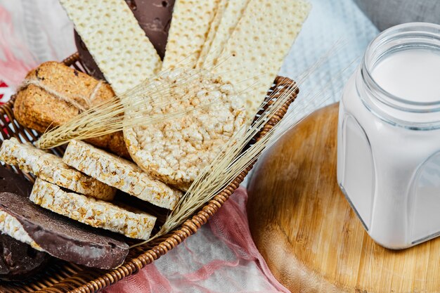 Biscoitos e um pote de leite sobre uma toalha de mesa.