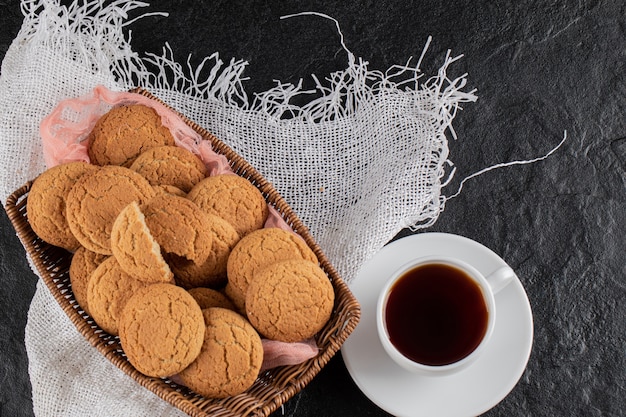 Biscoitos em uma travessa de madeira servidos com uma xícara de chá.