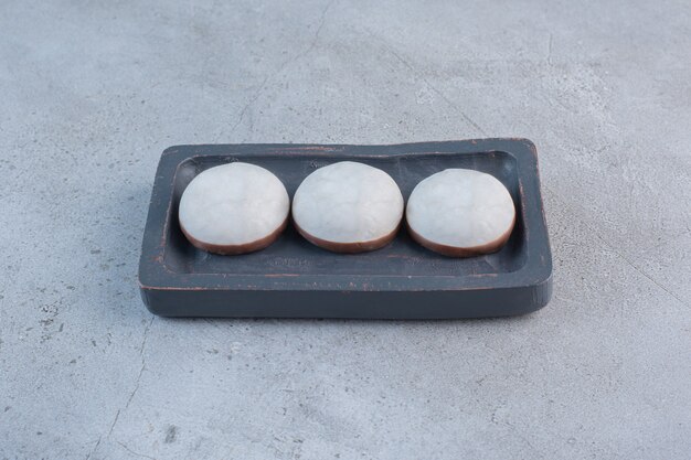 Biscoitos esmaltados redondos na placa preta na mesa de pedra.