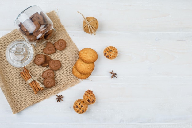 Biscoitos marrons em uma jarra, canela em um jogo americano com biscoitos brancos