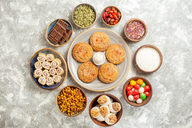 Biscoitos saborosos de vista de cima com rolinhos doces sobre fundo branco claro