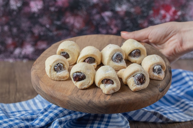 Biscoitos tradicionais com confiture de morango em uma placa de madeira.