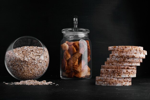 Foto grátis biscoitos, uma xícara de grãos e fuits secos em preto.