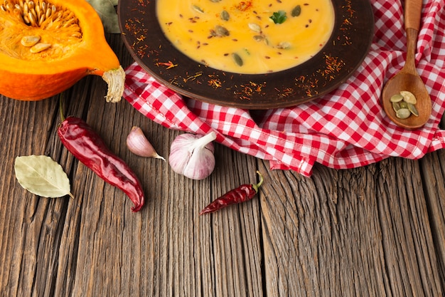 Foto grátis bisque de abóbora de alto ângulo e colher de pau com ingredientes