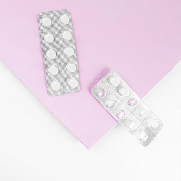 Blister usado com comprimidos em fundo branco e rosa