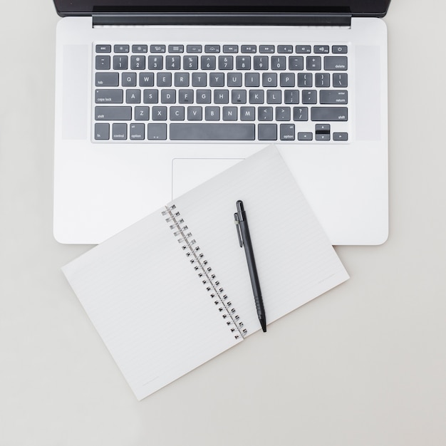 Foto grátis bloco de notas em branco com caneta sobre o teclado do laptop