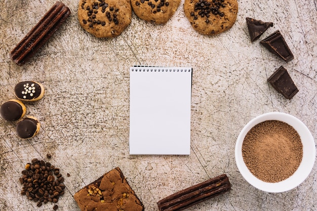 Bloco de notas entre grãos de café, biscoitos e chocolates