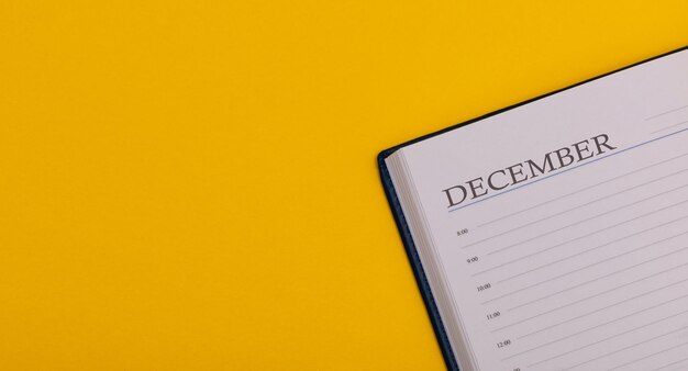 Bloco de notas ou diário com fundo amarelo calendário para dezembro tempo de inverno espaço para texto
