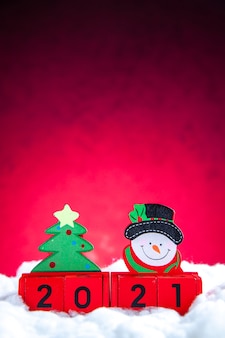 Blocos de madeira de vista frontal com um pequeno boneco de neve e uma árvore de natal em fundo vermelho