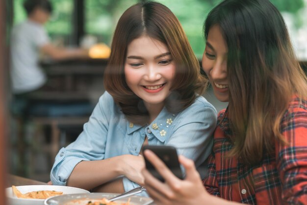 Blogger bonito feliz das mulheres asiáticas dos amigos que usa a foto do smartphone e que faz o vídeo do vlog do alimento