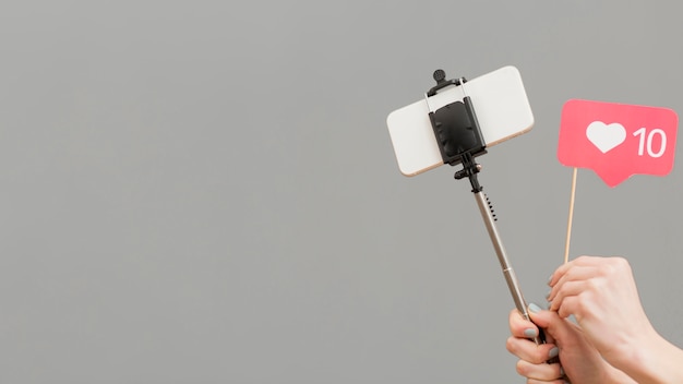 Blogger de close-up, segurando a vara selfie com telefone móvel