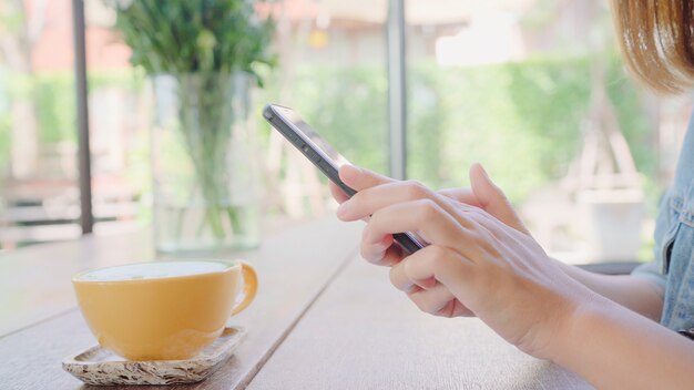 Blogger fêmea que fotografa o copo de chá verde no café com seu telefone.