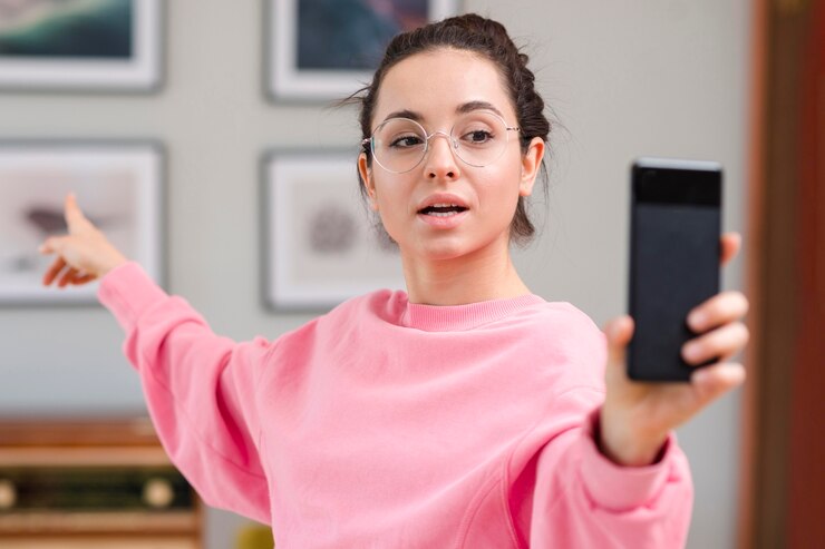 Foto grátis blogger segurando o smartphone e apontando para fora