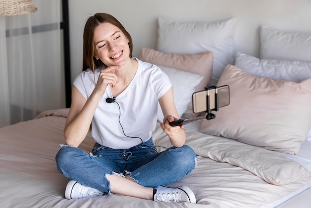 Blogger sentado na cama e gravando a si mesma