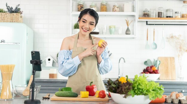 Blogueira de comida asiática cozinhando salada na frente da câmera do smartphone durante a gravação do vlog