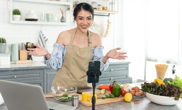 Blogueira de comida asiática cozinhando salada na frente da câmera do smartphone enquanto grava o vídeo do vlog