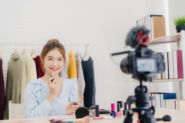 Blogueiro de beleza apresenta cosméticos de beleza enquanto está sentado na câmera frontal para gravação de vídeo