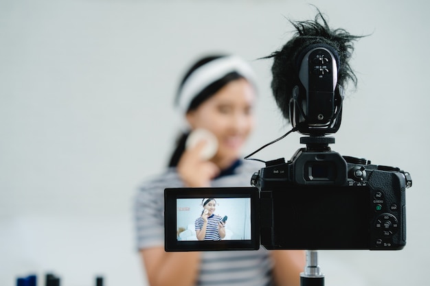 Blogueiro de beleza apresenta cosméticos de beleza enquanto está sentado na câmera frontal para gravação de vídeo