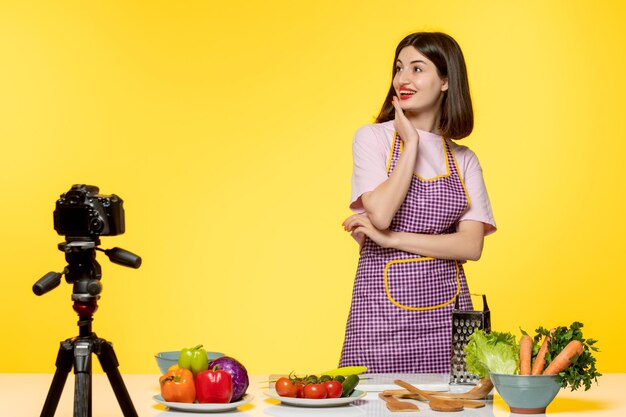 Blogueiro de comida fofo e adorável chef em avental rosa gravando vídeo para mídias sociais olhando para cima pensando