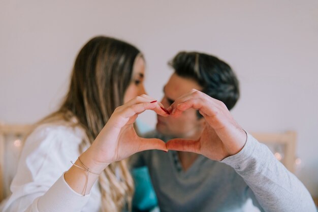 Blurred couple showing heart gesture