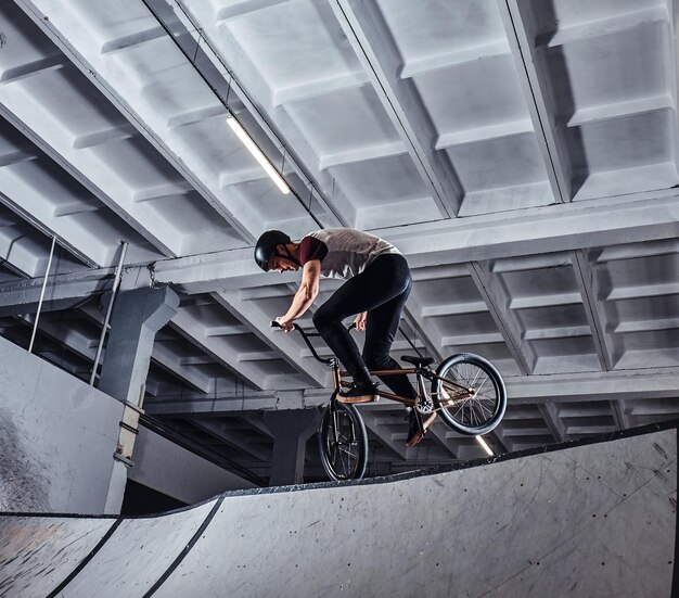 BMX freestyle. Jovem BMX fazendo truques em sua bicicleta no skatepark dentro de casa