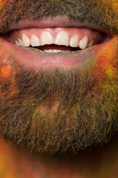 Boca de toothy sorridente homem barbudo com tinta de arco-íris no rosto