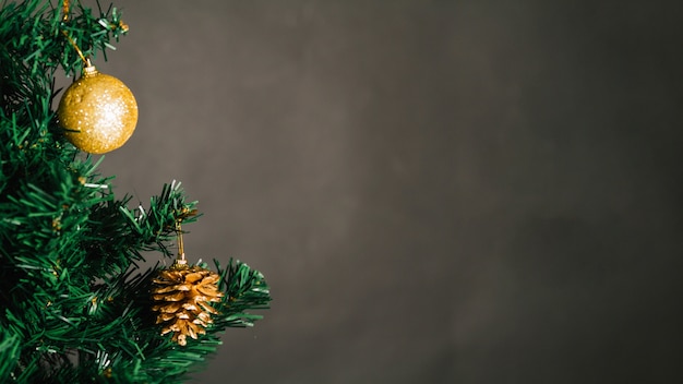 Bola de Natal dourada e cone de pinho na árvore