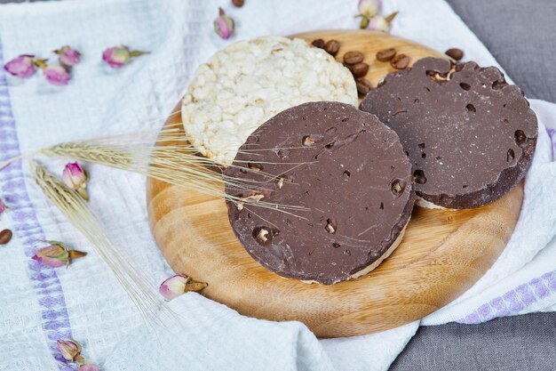 Bolachas de arroz e chocolate em uma placa de madeira com uma toalha de mesa.