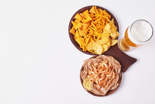 Bolachas e batatas fritas com um copo de cerveja.