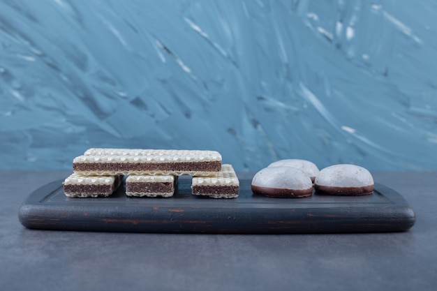 Foto grátis bolachas e bolos em uma bandeja de madeira na mesa de mármore.