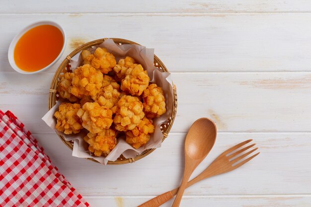 Bolas de camarão cobertas com à milanesa frita na superfície de madeira branca.