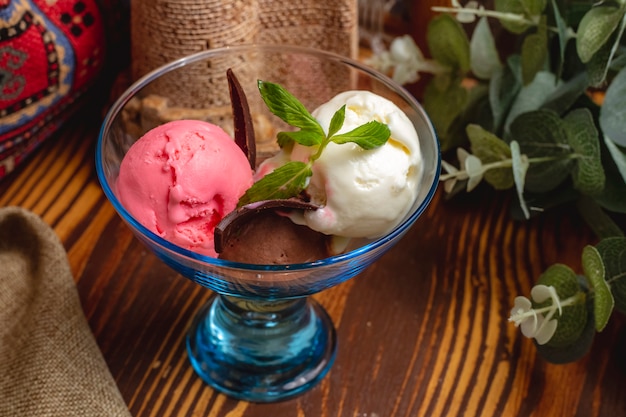 Foto grátis bolas de gelo crem decoradas com hortelã em um vaso de vidro em uma mesa de madeira