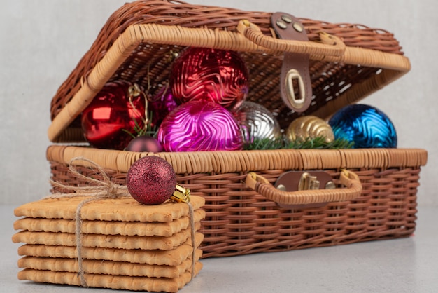 Bolas de natal coloridas na cesta com biscoitos na corda.