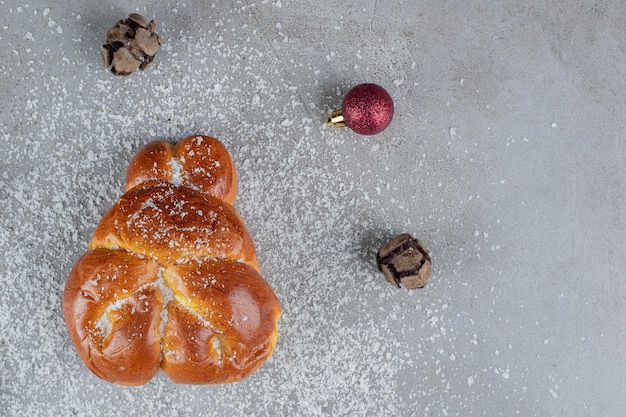 Bolas de natal e pinho em torno de um pão doce na mesa de mármore.