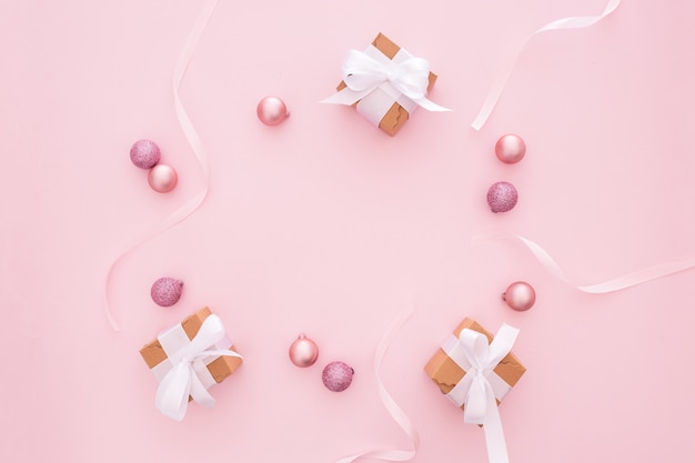 Bolas de natal e presentes em um fundo rosa Foto gratuita