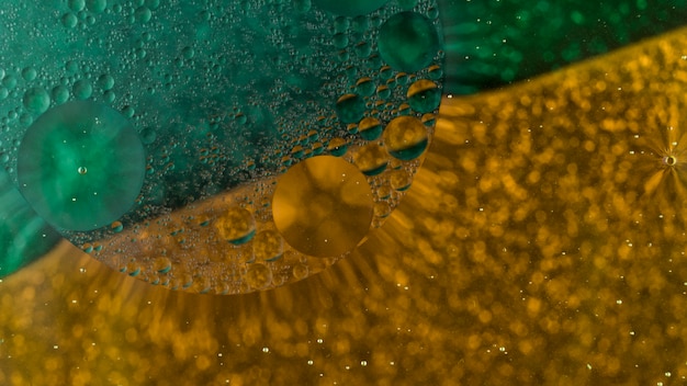 Bolhas de óleo flutuando sobre fundo verde e dourado abstrato