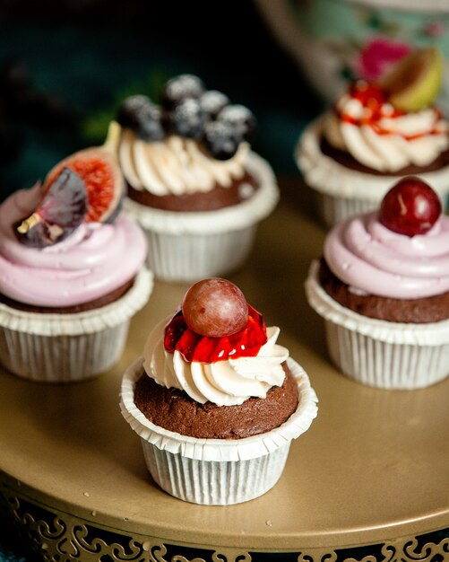 Bolinhos de chocolate decorados com creme de baunilha, figos, mirtilos e uvas