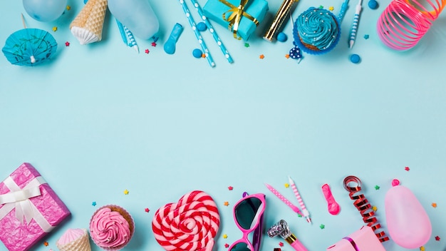 Bolinhos de cor azul e rosa; caixas de presente; pirulito; velas; serpentina e balão em pano de fundo azul