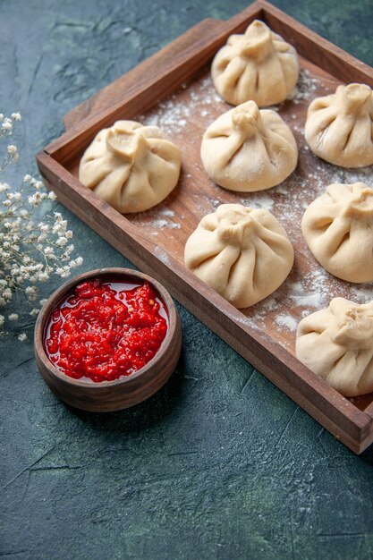 Bolinhos de massa crus com carne dentro em uma superfície cinza escura de frente para cozinhar prato farinha pimenta massa carne carne