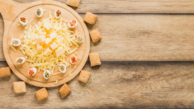 Bolinhos de queijo rodeado perto da tábua de madeira com queijo na mesa