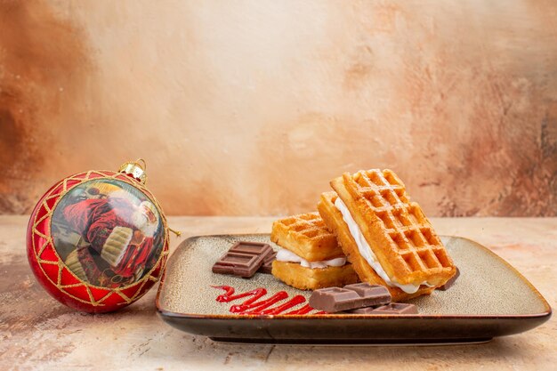 Bolinhos de waffle gostosos de vista frontal com barras de chocolate no fundo marrom