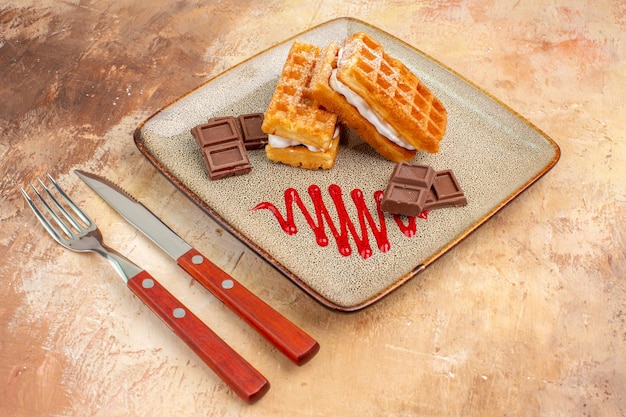 Foto grátis bolinhos de waffle gostosos de vista frontal com barras de chocolate no fundo marrom