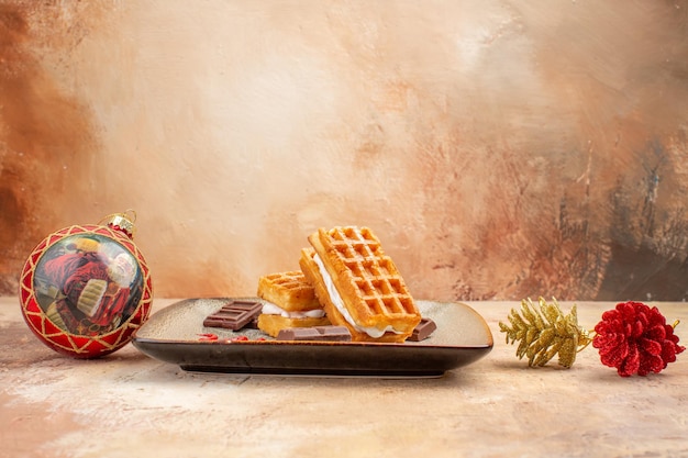 Bolinhos de waffle gostosos de vista frontal com barras de chocolate no fundo marrom