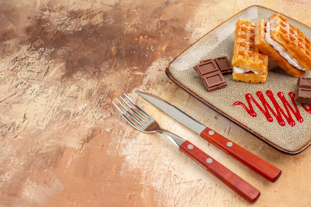 Bolinhos de waffle gostosos de vista frontal com barras de chocolate no fundo marrom