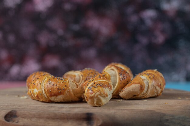 Bolinhos fritos de mini croissant em uma placa de madeira.