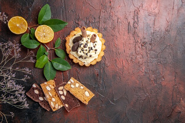 Bolo cremoso com torta e biscoito doce de mesa escura com vista de cima