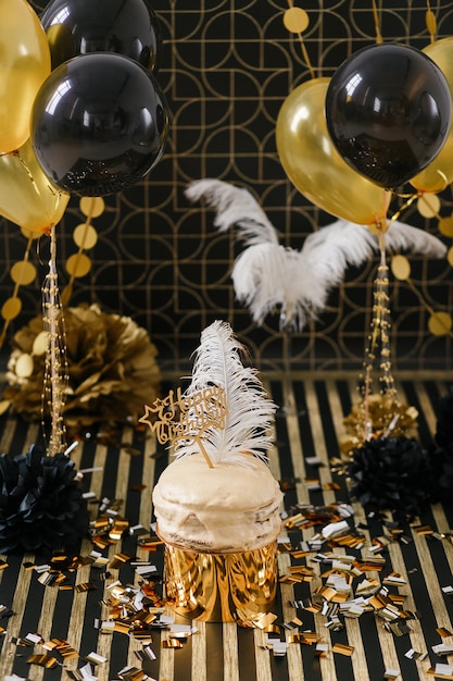 Bolo da festa de anos com os vários balões dourados e pretos da decoração.